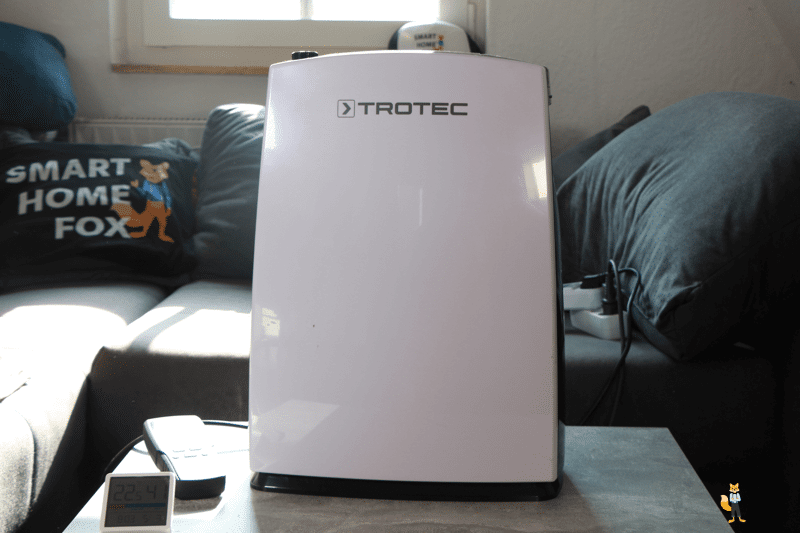 Der Trotec TTK 71E steht auf einem Couchtisch vor einer Couch und man sieht die übersichtliche Bedienoberfläche.